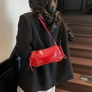 Glossy red faux leather shoulder bag with side bow detail on black blazer model