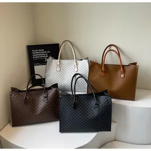 Dettaglio di borse tote con monogramma in nero, marrone e grigio su espositori bianchi