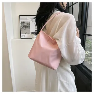 Shoulder view of pink bucket bag with white embroidery and slender straps on a model
