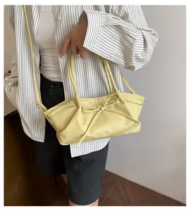 Detail of a creamy yellow woven handbag with bow tie decoration and soft pleated texture