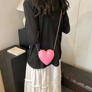 Sac à bandoulière chic rose en forme de cœur avec chaîne dorée sur un modèle