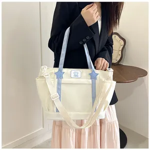 Detail of multi-functional cream tote bag with blue star accents and adjustable wide strap