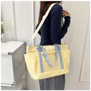 Detail of yellow canvas tote bag featuring transparent front pocket and blue straps