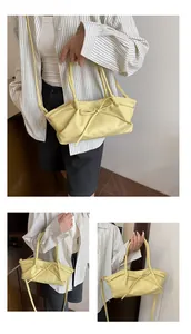 Detailed close-up of light yellow woven handbag with bow decoration and adjustable strap