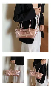 Close-up of pink metallic woven handbag with bow detail and adjustable shoulder strap