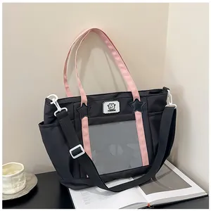 Detail of black canvas tote bag with clear PVC front pocket and pink handles