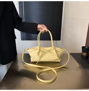 Detail of light yellow woven bag featuring a stylish bow and elegant pleated texture