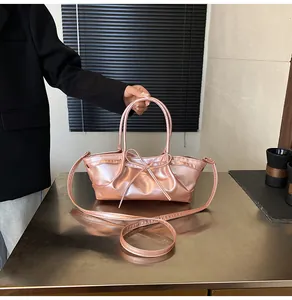Detailed close-up of pink metallic handbag with bow accent and stylish pleated sides