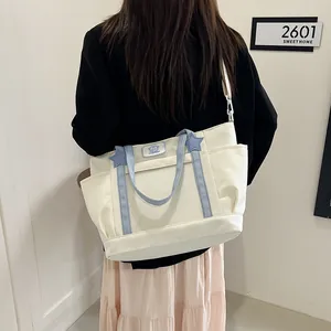 Minimalist cream and blue canvas tote bag with star details shown on shoulder