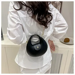 Detail der schwarzen Halbmondtasche mit goldener Kette und Schnalle an einem Model