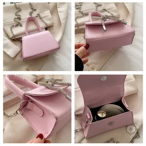 Detail van roze mini-tas met strass-strikje en zilveren metalen ketting schouderriem