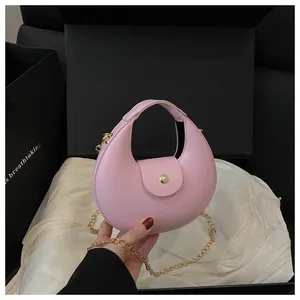 Detailansicht der rosa Halbmondtasche mit goldener Kette und Magnetverschluss auf Seide