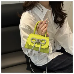 Détail du mini sac carré vert néon avec nœud en strass étincelant et bandoulière chaîne