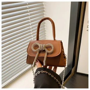 Détail du mini sac bandoulière marron avec nœud en strass et chaîne en argent pur