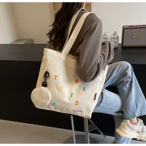 Détail du sac cabas en toile avec broderie colorée et petit porte-monnaie assorti