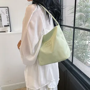 Minimalist mint green bucket bag for women with embroidered strap on model shoulder