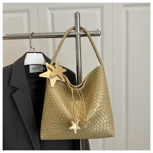 Detalle de bolso tejido dorado con colgantes de estrellas y textura cuero metálico