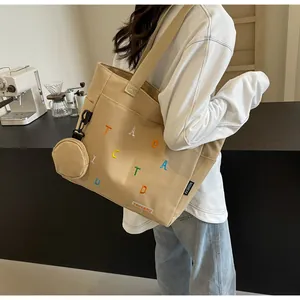 Détail du sac cabas en toile kaki avec broderie colorée et petit porte-monnaie suspendu