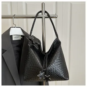 Detalle de la textura de cuero negro trenzado y elegantes colgantes de estrella en el bolso