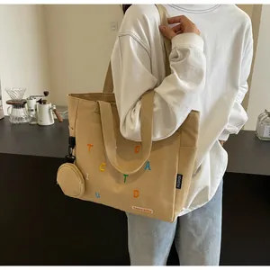 Détail du sac fourre-tout en toile kaki avec broderie et mini pochette à monnaie
