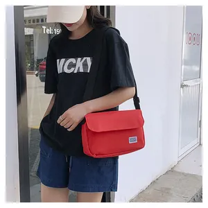Detail of red canvas messenger bag featuring a wide adjustable black nylon shoulder strap