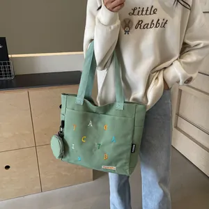 Sac cabas en toile verte avec broderie colorée et pochette ronde assortie sous lumière