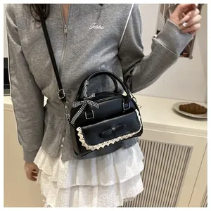 Détail du sac à main en cuir PU noir avec nœud en dentelle et ruban à carreaux sur l'anse