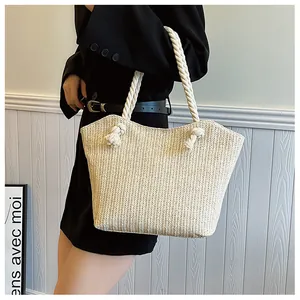 Détail du sac de plage beige tissé avec anses en corde de coton et texture en V