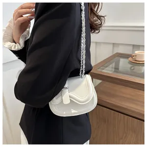 Detail of white leather saddle bag with woven silver chain strap on black blazer