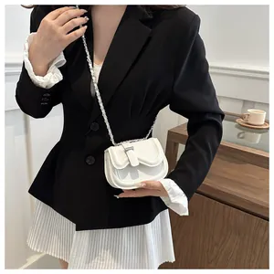 Mini white leather crossbody bag with silver chain strap worn by a model in interior