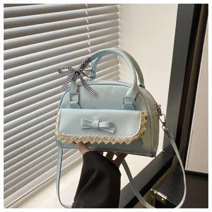 Détail du sac à bandoulière bleu clair avec bordure en dentelle et nœud à carreaux chic