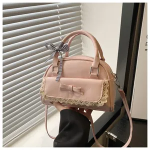 Détail du sac bandoulière rose avec bordure en dentelle et nœud à carreaux noir blanc