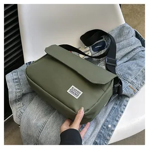 Detail of army green canvas messenger bag with adjustable strap on denim jacket