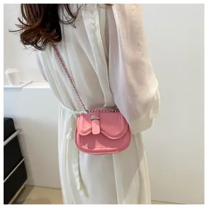 Close-up of pink mini saddle bag with wavy flap and silver chain strap on model