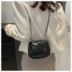 Side view of a black leather saddle bag with wavy flap and silver chain on model