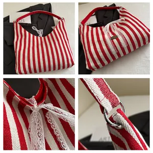 Detail view of red striped canvas hobo bag with lace bow and oval metal nameplate