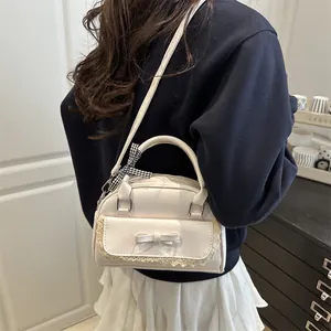 Sac bandoulière minimaliste blanc crème avec nœud et dentelle porté par un mannequin