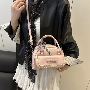 Sac à main Boston rose avec bordure en dentelle et nœud porté par un mannequin de mode