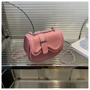 Detail of pink saddle bag with wave-cut flap and silver chain strap on a modern shelf