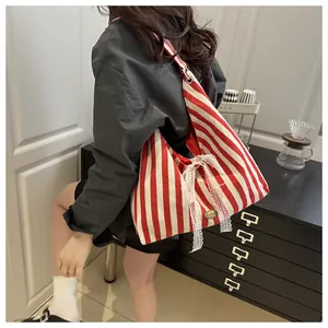 Close-up of red striped canvas tote with white lace bow and handmade metal tag