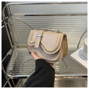 Detail of beige faux leather crossbody bag with wave flap and silver metal lock