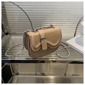 Detail of beige saddle bag with wavy flap edge and silver chain strap for women