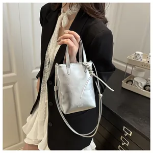Silberne Metallic-Eimertasche mit FASHION BAGS-Aufdruck und Knotendetails seitlich