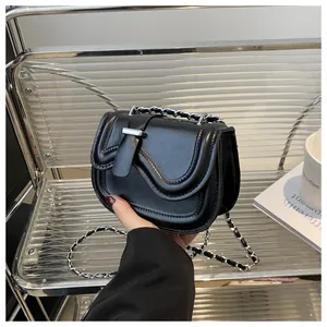 Close-up of a black glossy saddle bag with chain strap and elegant silver hardware details