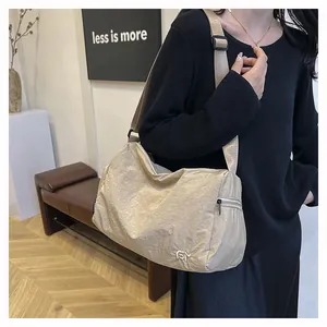 Détail du sac bandoulière beige avec texture plissée et large bandoulière réglable