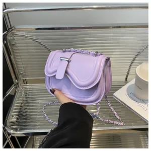 Detail view of purple leather saddle bag with silver metal bar buckle and chain strap