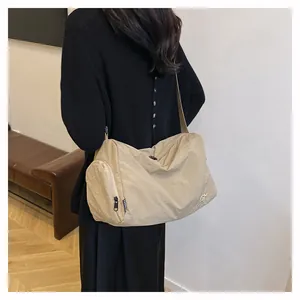 Détail du sac bandoulière en nylon beige avec poche zippée et broderie fashion