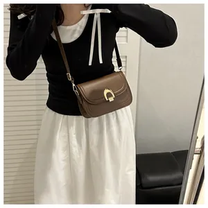 Bolso de montura marrón con hebilla dorada mostrado en selfie de espejo como bandolera