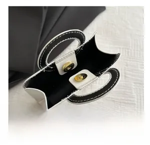Detailed top view of a mini trapezoid handbag featuring contrast stitching and gold metal buckle