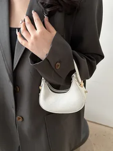 Close-up of a white lychee grain leather crescent mini bag with gold hardware